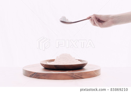Hand pouring flour into wooden bowl with wooden spoon Hand pouring flour into wooden bowl with wooden spoon 83869210