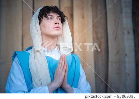Portrait of an androgynous virgin mary praying while looking up 83869383