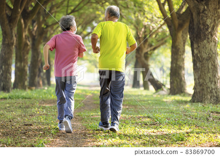 Rear view Senior couple face mask jogging i park Rear view Senior couple face mask jogging i park 83869700