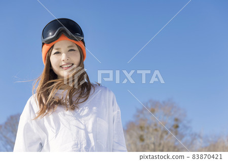 A young woman looking up at a ski resort, a snowboard image 83870421