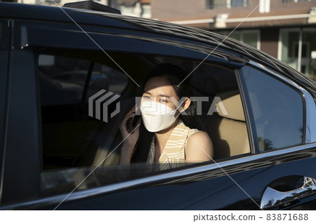 Young asian woman talking on mobile phone while sitting in a taxi. 83871688