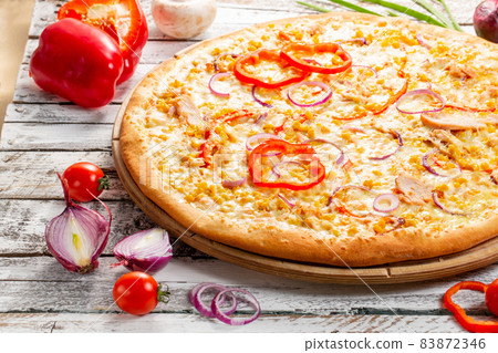 Pizza with chicken, paprika and corn. Italian kitchen and cooking concept. Chief with a pizza cutter cutting pizza to pieces at Neapolitan pizzeria. Pizza with chicken, paprika and corn. Italian kitchen and cooking concept. Chief with a pizza cutter cutting pizza to pieces at Neapolitan pizzeria. 83872346