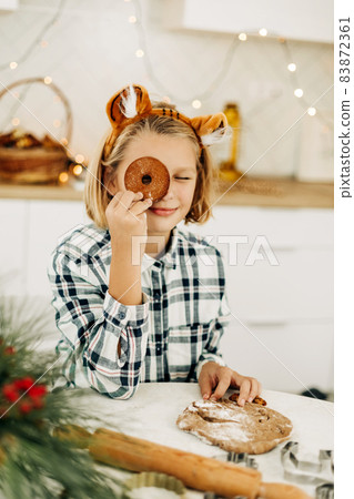 A cheerful girl hides her eyes behind Christmas cookies. Preparation for the holidays, Christmas spirit, Christmas treats A cheerful girl hides her eyes behind Christmas cookies. Preparation for the holidays, Christmas spirit, Christmas treats 83872361
