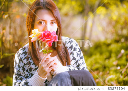 Beautiful girl in a cute pose with the cut flowers of the autumn rose Beautiful girl in a cute pose with the cut flowers of the autumn rose 83873104