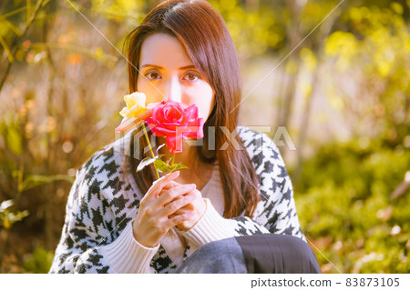 一個逗人喜愛的姿勢的美麗的女孩與秋天玫瑰的切花 一個逗人喜愛的姿勢的美麗的女孩與秋天玫瑰的切花 83873105