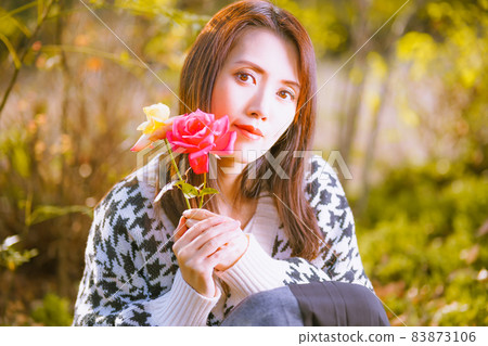 一個逗人喜愛的姿勢的美麗的女孩與秋天玫瑰的切花 一個逗人喜愛的姿勢的美麗的女孩與秋天玫瑰的切花 83873106