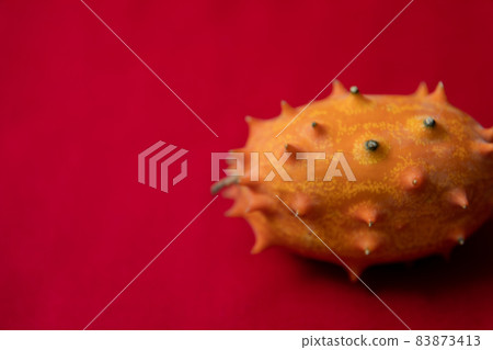 Kiwano 圖像照片的怪異水果紅色背景 83873413