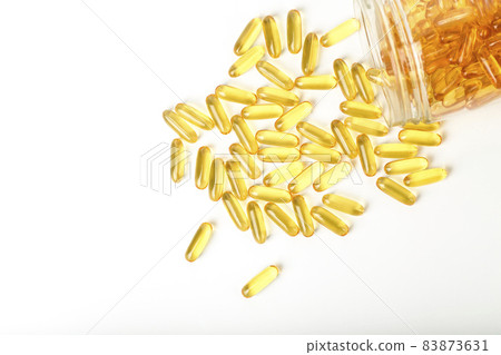 Fish oil in gelatin capsules isolate. Omega vitamins in golden colored pills on a blank white background. Medicine, pharmacy, drugs and multivitamins oils concept 83873631