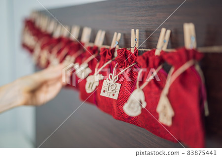 Woman making Christmas advent calendar. Pouches on a rope 83875441