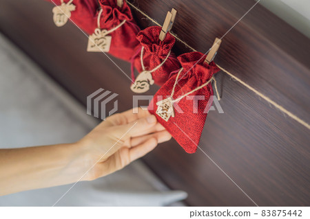 Woman making Christmas advent calendar. Pouches on a rope Woman making Christmas advent calendar. Pouches on a rope 83875442