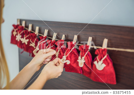 Woman making Christmas advent calendar. Pouches on a rope 83875455