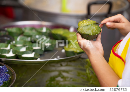 people making traditional Thai glutinous rice flour sweet pandan leaf scent dessert in banana leaf cup 83876783