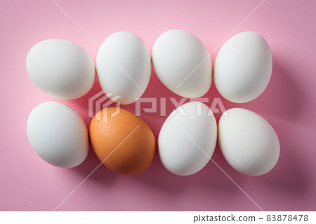 White and brown raw chicken eggs on pink background. 83878478