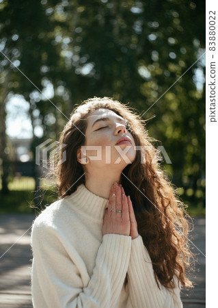 Young brunette woman meditating outdoors with her eyes closed 83880022