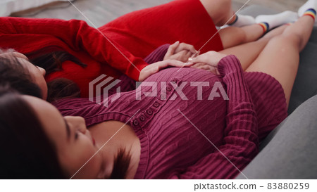 Happy pregnant lesbian couple spending time together at home. Happy pregnant lesbian couple spending time together at home. 83880259