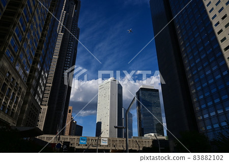 Airplanes fly over Shinjuku skyscrapers High autumn sky and white clouds 83882102