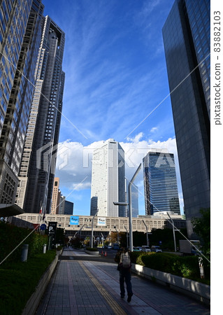 垂直位置 新宿摩天大樓 飛機從頭頂飛過 摩天大樓和秋天的天空 白雲流 83882103