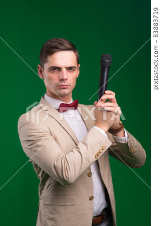 The entertainer. Young elegant talking man holding microphone, Isolated in studio. The entertainer. Young elegant talking man holding microphone, Isolated in studio. 83883719