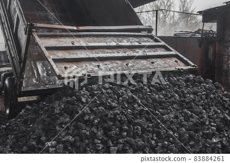 The dump truck unloaded a pile of coking coal from the body in the industrial zone. Cargo transportation and industry The dump truck unloaded a pile of coking coal from the body in the industrial zone. Cargo transportation and industry 83884261