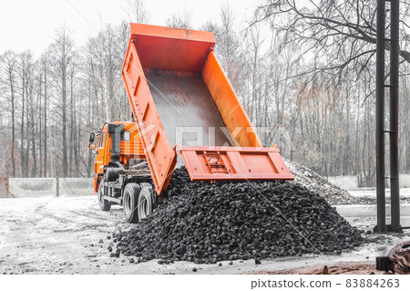 Dump truck in the industrial zone unloads coking coal from the body Dump truck in the industrial zone unloads coking coal from the body 83884263