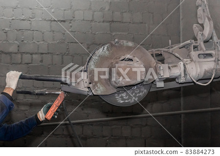 A hand's of a man controls heavy equipment with grinding stone to clean reinforced concrete structures in a workshop of an industrial plant A hand's of a man controls heavy equipment with grinding stone to clean reinforced concrete structures in a workshop of an industrial plant 83884273