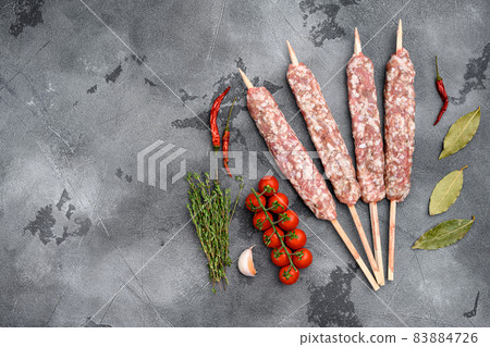 Fresh Raw kofta or lula kebabs skewers, with grill ingredients, on gray stone table background, top view flat lay, with copy space for text Fresh Raw kofta or lula kebabs skewers, with grill ingredients, on gray stone table background, top view flat lay, with copy space for text 83884726