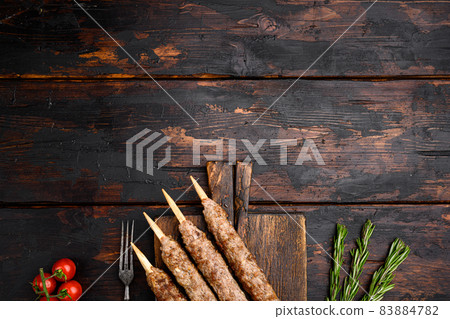 Tikka, shish and kofta kebabs, on serving board, on old dark wooden table background, top view flat lay, with copy space for text Tikka, shish and kofta kebabs, on serving board, on old dark wooden table background, top view flat lay, with copy space for text 83884782