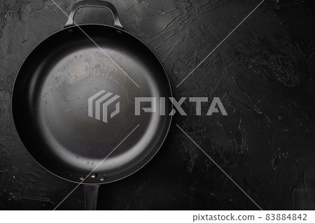 Cast iron frying pan with copy space for text or food with copy space for text or food, top view flat lay , on black dark stone table background Cast iron frying pan with copy space for text or food with copy space for text or food, top view flat lay , on black dark stone table background 83884842