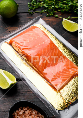 Fresh raw salmon fish steak in vacuum pack, with herbs, on old dark wooden table background Fresh raw salmon fish steak in vacuum pack, with herbs, on old dark wooden table background 83884859