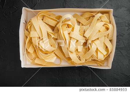 Raw pappardelle, on black dark stone table background, top view flat lay Raw pappardelle, on black dark stone table background, top view flat lay 83884933