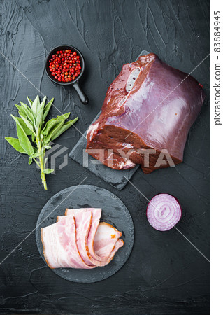 Raw beef liver with bacon on black background, flat lay Raw beef liver with bacon on black background, flat lay 83884945