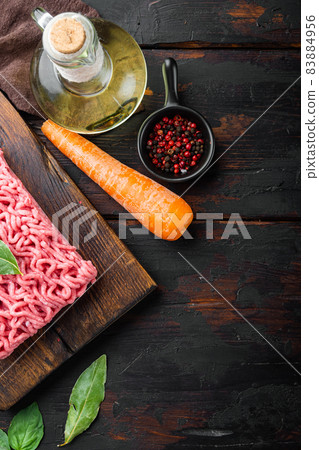 Ingredients for cooking Bolognese sauce, minced beef meat tomatoe and herbs, on wooden cutting board, on old dark wooden table background, top view, flat lay, with copy space for text Ingredients for cooking Bolognese sauce, minced beef meat tomatoe and herbs, on wooden cutting board, on old dark wooden table background, top view, flat lay, with copy space for text 83884956