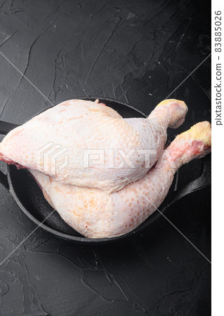 Raw chicken legs , in frying cast iron pan, on black stone background, with copy space for text 83885026