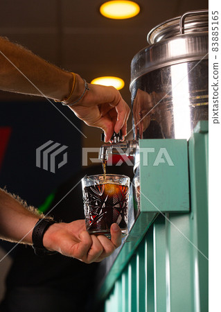 Barman pouring a vermut from a barrel into a glass Barman pouring a vermut from a barrel into a glass 83885165