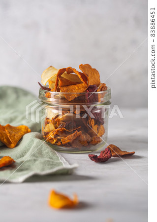 Vegetable chips are in a jar and placed on a concrete background with a napkin Vegetable chips are in a jar and placed on a concrete background with a napkin 83886451