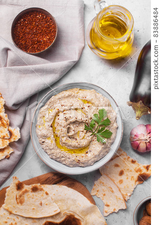 Baba ganush from baked eggplant with sesame paste with ingredients on a concrete background close up top view Baba ganush from baked eggplant with sesame paste with ingredients on a concrete background close up top view 83886484