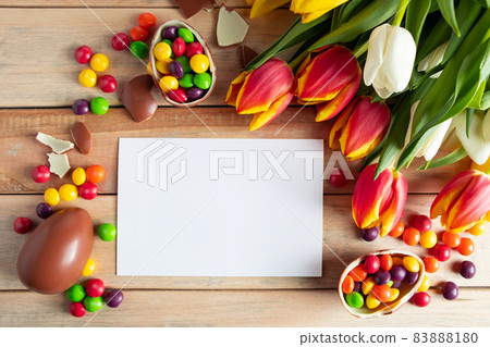 Easter composition of sweet chocolate eggs and tulips. Empty greeting card for festive design. Easter composition of sweet chocolate eggs and tulips. Empty greeting card for festive design. 83888180