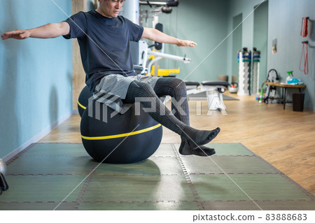 A man riding a balance ball in a gym 83888683