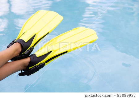 Female legs in flippers on blue water background. Concept of summer vacation. 83889953