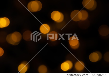 Defocused bokeh lights on black background, an abstract naturally blurred backdrop for Christmas eve or birthday party. Festive light texture. Yellow and red garland in blur. Overlay effect for design 83890236