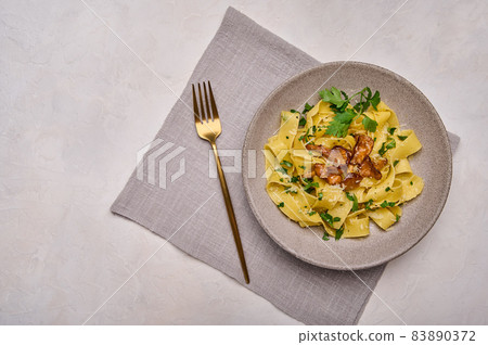 Italian pasta pappardelle with mushrooms chanterelles, cheese and parsley on plate with golden fork Italian pasta pappardelle with mushrooms chanterelles, cheese and parsley on plate with golden fork 83890372