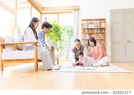 Three-generation family relaxing in the living room 83891327