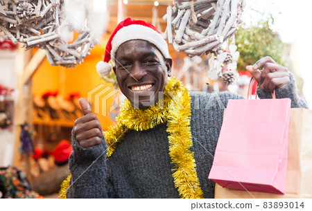 Laughing guy in Santa hat after Christmas shopping Laughing guy in Santa hat after Christmas shopping 83893014
