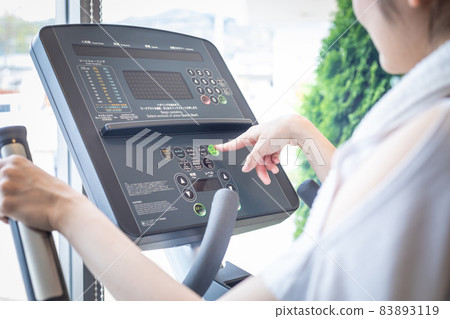 Female operating the panel of a walking machine 83893119