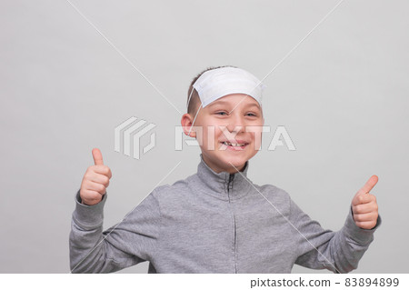 a cute 8-10-year-old boy is laughing. he put a medical protective mask on his forehead and shows class. on a white background close-up a cute 8-10-year-old boy is laughing. he put a medical protective mask on his forehead and shows class. on a white background close-up 83894899