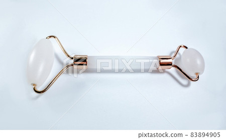White massage quartz roller for the face close-up isolated on a white background. Beauty and care concept for women White massage quartz roller for the face close-up isolated on a white background. Beauty and care concept for women 83894905