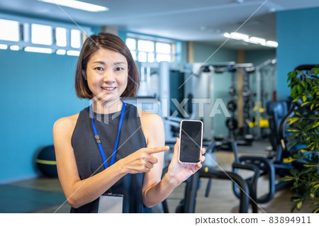 Sports trainer (smartphone) working at a sports gym Sports trainer (smartphone) working at a sports gym 83894911