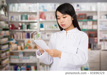Chinese woman pharmacist keeps track of drugs in interior of pharmacy Chinese woman pharmacist keeps track of drugs in interior of pharmacy 83896329