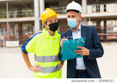 Civil engineers in masks checking work process Civil engineers in masks checking work process 83896421