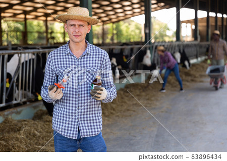 Male farmer standing with syringe at farm Male farmer standing with syringe at farm 83896434